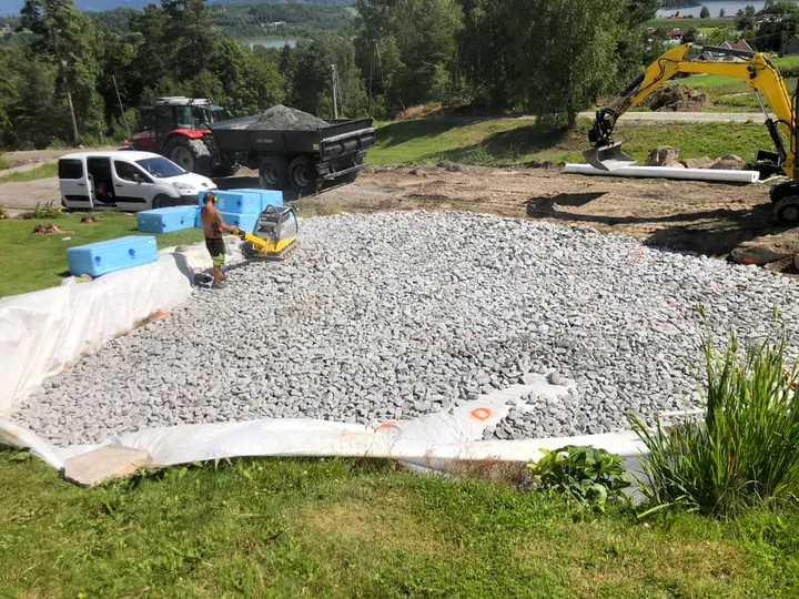 Pukk planeres og komprimeres med vibroplate på en byggetomt